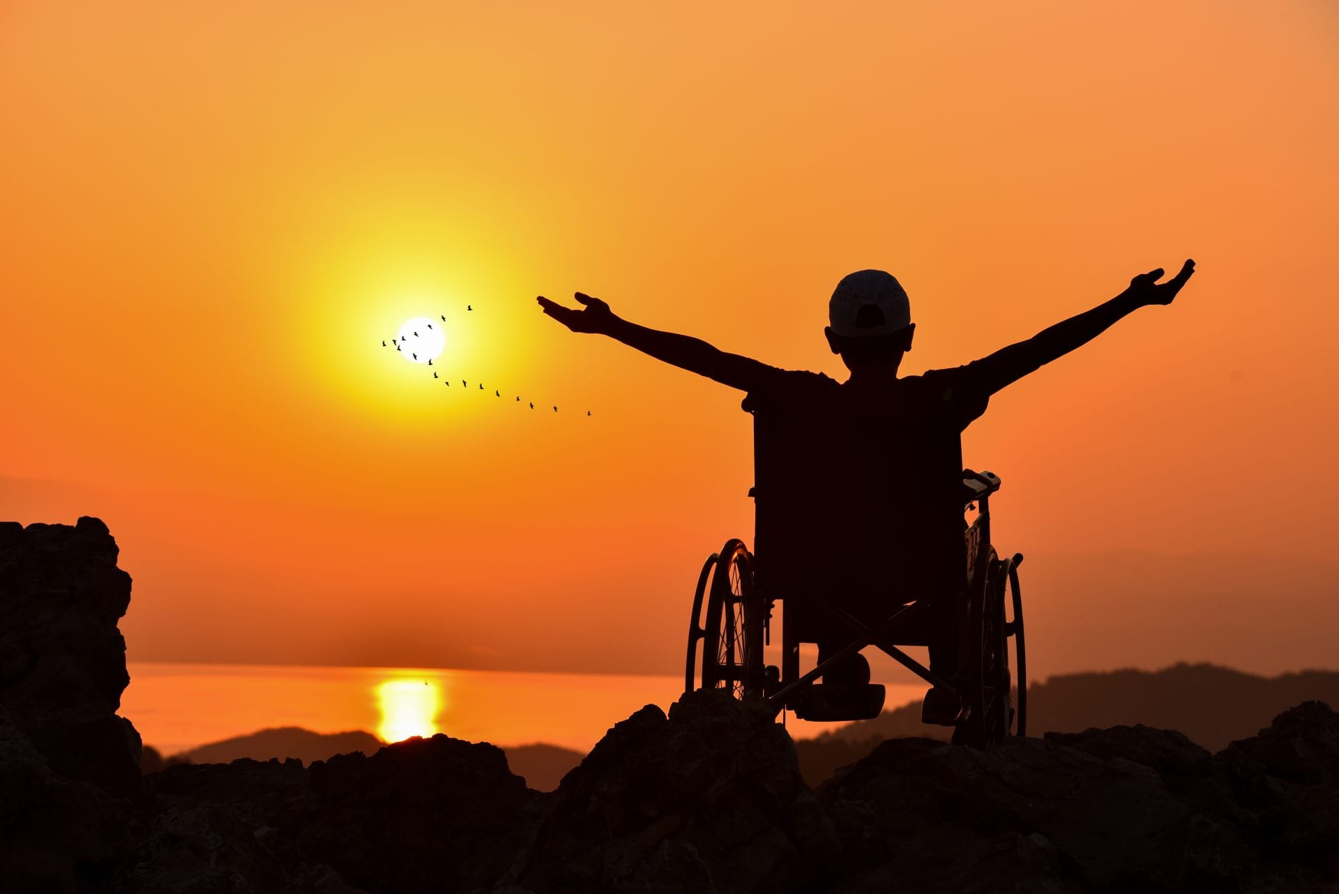 Silhouette of a person in a wheelchair at sunset